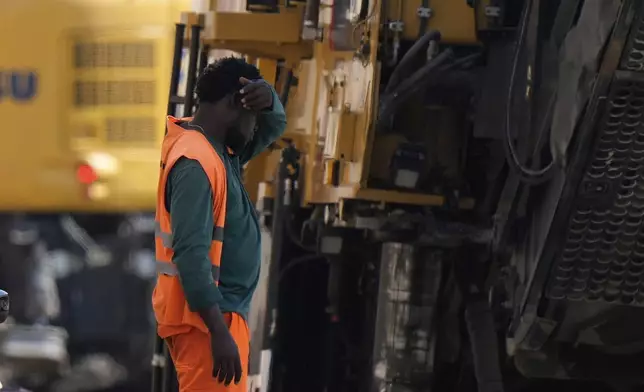 FILE - An employee takes a break as he works at a road construction site in Milan, Italy, July 1, 2025. (AP Photo/Luca Bruno, File)