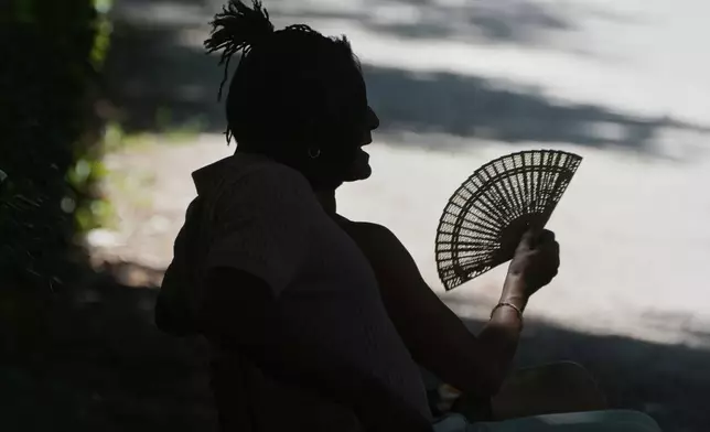 FILE - A man fans himself as he rests on a hot day in Retiro Park in Madrid, Spain, June 28, 2025. (AP Photo/Paul White, File)
