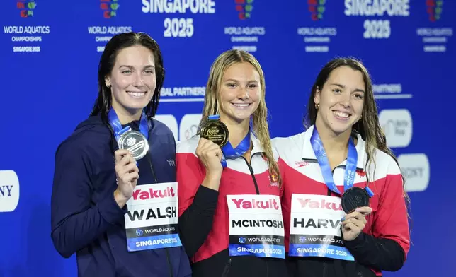 Gold medalist Summer McIntosh of Canada, center, flanked by silver medalist Alex Walsh of the United States, left, and bronze medalist Mary-Sophie Harvey of Canada pose on the podium after the women's 200-meter individual medley final at the World Aquatics Championships in Singapore, Monday, July 28, 2025. (AP Photo/Vincent Thian)