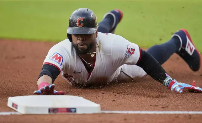 Cleveland Guardians' Carlos Santana slides safely into third base on a hit by Lane Thomas in the first inning of a baseball game against the Detroit Tigers in Cleveland, Friday, July 4, 2025. (AP Photo/Sue Ogrocki)
