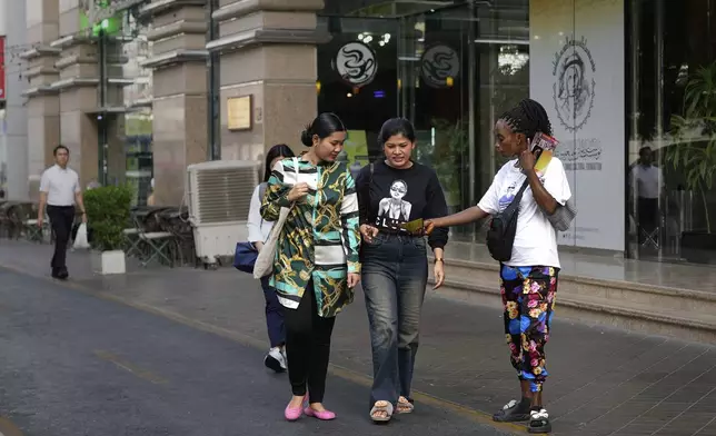 A migrant worker hands out beauty salon pamphlets to passersby at a marketplace in Dubai, United Arab Emirates, Friday, July 4, 2025. (AP Photo/Altaf Qadri)