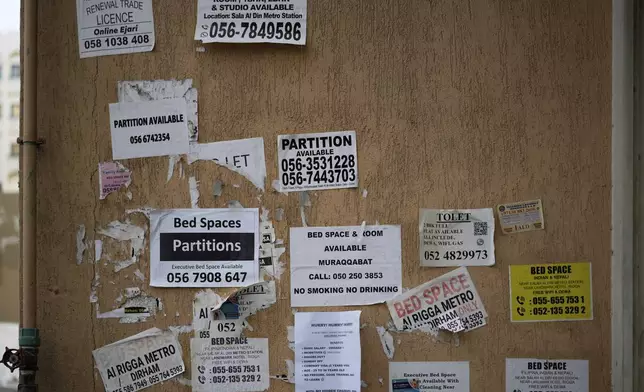 The wall of a building is plastered with advertisements for inexpensive, partitioned housing in Dubai, United Arab Emirates, Friday, July 4, 2025. (AP Photo/Altaf Qadri)