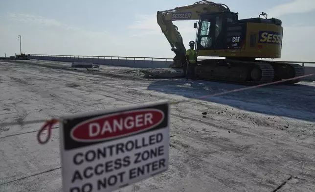 A demolition crew removes slabs of concrete from the remaining portions of the Francis Scott Key Bridge, Wednesday, July 30, 2025, in Baltimore. (AP Photo/Stephanie Scarbrough)