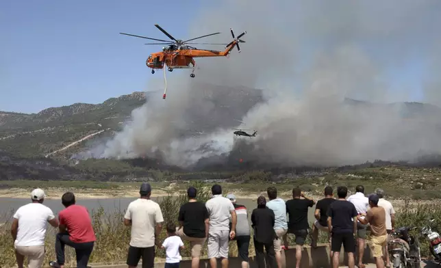 Helicopters spray water to extinguish a fire in Seferihisar, near Izmir, Turkey, Monday, June 30, 2025. (Cengiz Malgir/Dia Photo via AP)