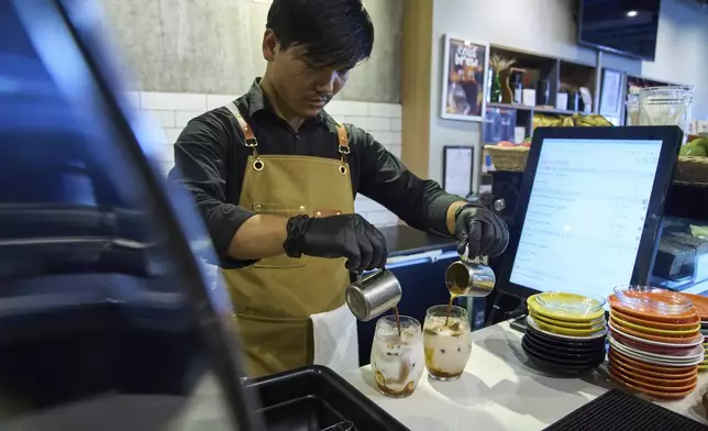 An employee prepares a coffee for a customer at Himalayan Java cafe at Boudhanath Stupa in Kathmandu, Nepal, Tuesday, June 10, 2025. (AP Photo/Niranjan Shrestha)