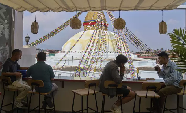 People drink coffee overlooking Boudhanath Stupa at Himalayan Java cafe in Kathmandu, Nepal, Tuesday, June 10, 2025. (AP Photo/Niranjan Shrestha)