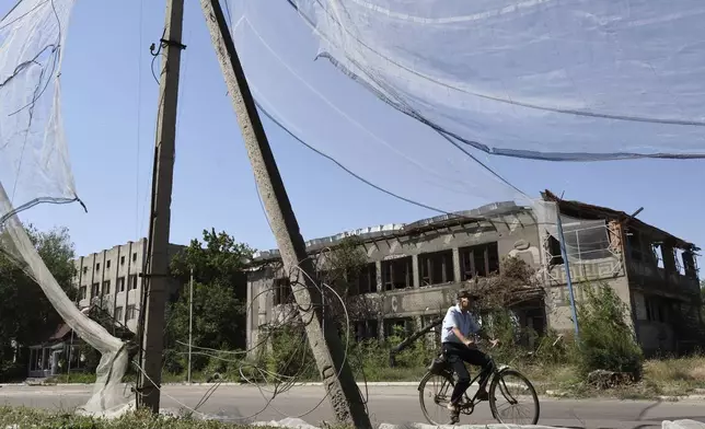 FILE - In this photo provided by Ukraine's 65th Mechanized Brigade press service, a resident rides a bike along the street under an anti-drone net in Orikhiv in Ukraine’s Zaporizhzhia region, July 15, 2025. (Andriy Andriyenko/Ukraine's 65th Mechanized Brigade via AP, File)