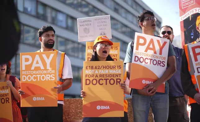 NHS resident doctors and supporters stand outside St Thomas' Hospital as resident doctors in England, formerly referred to as junior doctors, begin a five-day strike after talks with the Government collapsed over pay, in London, Friday, July 25, 2025. (James Manning/PA via AP)
