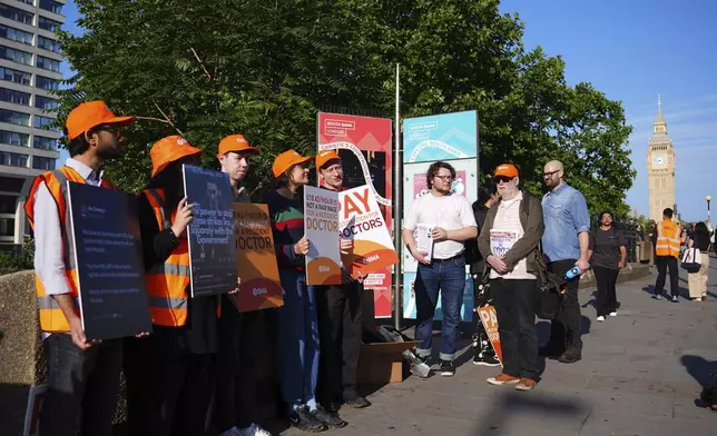 NHS resident doctors hold placards outside St Thomas' Hospital in London, as resident doctors in England, formerly referred to as junior doctors, begin a five-day strike after talks with the government collapsed over pay, Friday, July 25, 2025. ( James Manning/PA via AP)