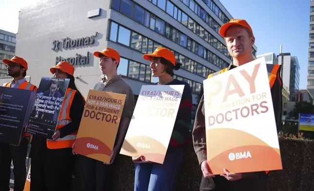NHS resident doctors hold placards outside St Thomas' Hospital in London, as resident doctors in England, formerly referred to as junior doctors, begin a five-day strike after talks with the government collapsed over pay, Friday, July 25, 2025. ( James Manning/PA via AP)