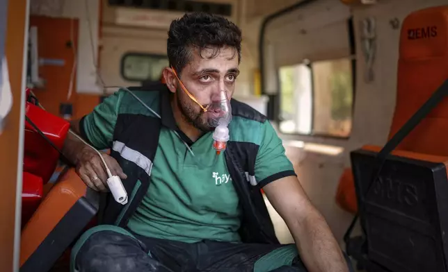 A member of the Alhayat Volunteer Team uses an oxygen mask while receiving treatment for smoke inhalation after participating in efforts to extinguish a wildfire near the town of Rabia, in Syria's Latakia countryside, early Monday, July 7, 2025. (AP Photo/Ghaith Alsayed)