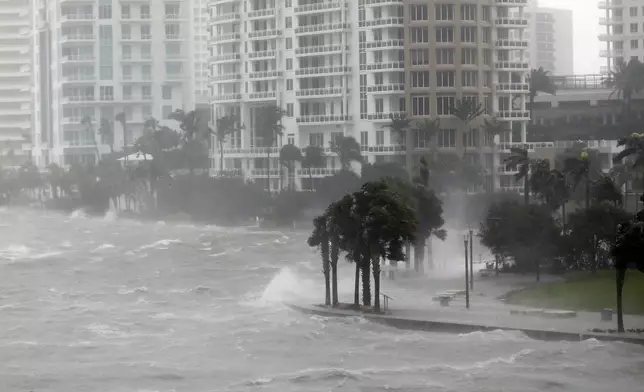 FILE- Waves crash over a seawall at the mouth of the Miami River from Biscayne Bay, Fla., as storm surge from Hurricane Irma impacts Miami on Sept. 10, 2017. (AP Photo/Wilfredo Lee,File)