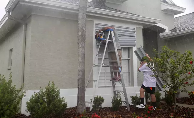FILE - Tim Mullen, and Michael Brissette, cover their windows with hurricane shutters in preparation for Tropical Storm Elsa, Tuesday, July 6, 2021 in Tampa, Fla. (Arielle Bader/Tampa Bay Times via AP,File)