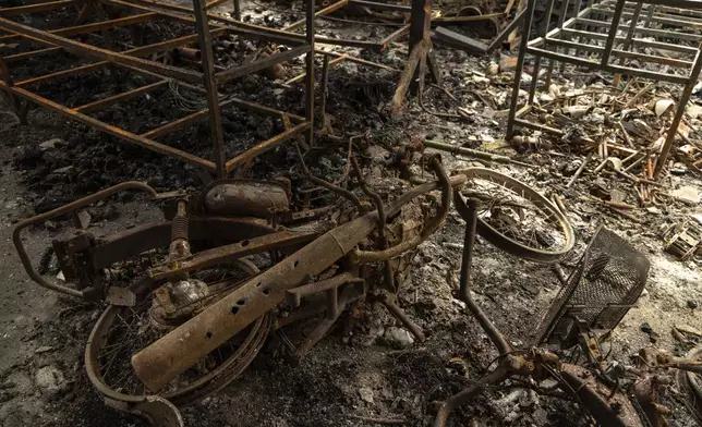 A torched motorcycle lies in ruins in a bombed building in O'Smach, Oddar Meanchey in Cambodia on Wednesday, July 30, 2025. (AP Photo/Anton L. Delgado)