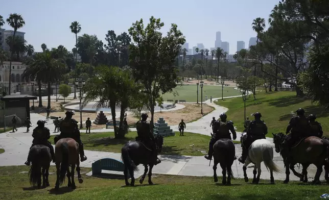 Federal agents ride on horseback at MacArthur Park Monday, July 7, 2025, in Los Angeles. (AP Photo/Damian Dovarganes)