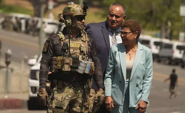 Los Angeles Mayor Karen Bass walks with a federal agent at MacArthur Park Monday, July 7, 2025, in Los Angeles. (AP Photo/Damian Dovarganes)