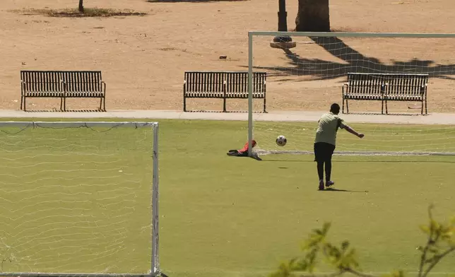 A boy kicks a soccer ball at MacArthur Park, Tuesday, July 8, 2025, in Los Angeles. (AP Photo/Damian Dovarganes)