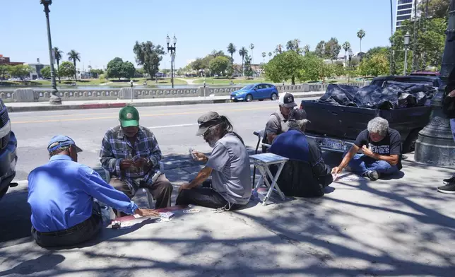 People play cards on a sidewalk at MacArthur Park, Tuesday, July 8, 2025, in Los Angeles. (AP Photo/Damian Dovarganes)
