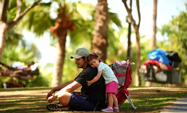 Miguel Hernandez is hugged by his one-year-old daughter Sayreli at MacArthur Park, Tuesday, July 8, 2025, in Los Angeles. (AP Photo/Damian Dovarganes)
