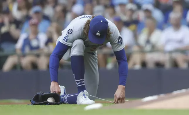 Los Angeles Dodgers starting pitcher Tyler Glasnow ties his shoe during the fifth inning of a baseball game against the Milwaukee Brewers, Wednesday, July 9, 2025, in Milwaukee. (AP Photo/Jeffrey Phelps)
