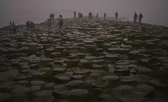 Tourists visit the Giant's Causeway, near Bushmills, County Antrim, Northern Ireland, Monday, July 21, 2025. (AP Photo/Francisco Seco)