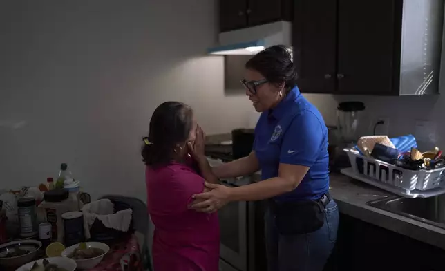 Martha, a mobile home resident, breaks down while speaking with Luz Gallegos, executive director of the immigrant and farmworker justice group TODEC, in Oasis, Calif., Monday, April 14, 2025, after picking up cases of bottled water provided by the organization. (AP Photo/Jae C. Hong)