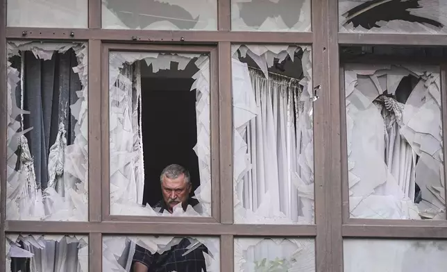 A man stands at the broken windows of his house after a Russian attack in Kyiv, Ukraine, Monday, July 21, 2025. (AP Photo/Efrem Lukatsky)