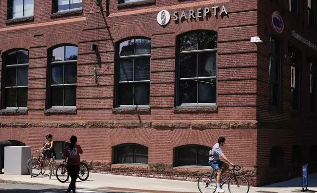 A cyclist passes the headquarters of Sarepta Therapeutics , Monday, July 28, 2025, in Cambridge, Mass. (AP Photo/Charles Krupa)
