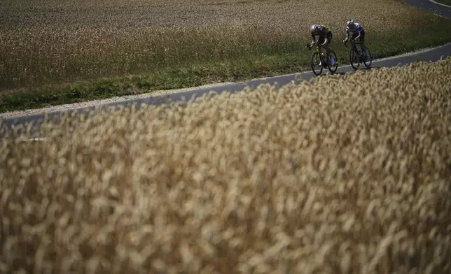 Belgium's Wout van Aert, left, and Spain's Pablo Castrillo Zapater ride past fields of wheat during the sixth stage of the Tour de France cycling race over 201.5 kilometers (125.2 miles) with start in Bayeux and finish in Vire Normandy, France, Thursday, July 10, 2025. (AP Photo/Thibault Camus)