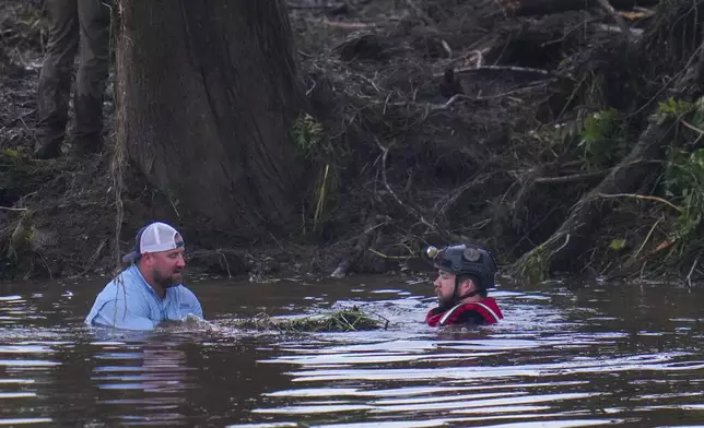 Officials are seen in the Guadalupe River as they assist in recovery efforts after a flash flood swept through the area Sunday, July 6, 2025, in Hunt, Texas. (AP Photo/Julio Cortez)
