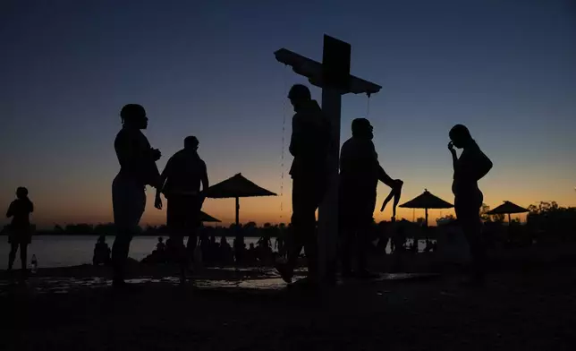 People take a shower in the late afternoon, as temperatures are expected to edge over 40 degrees Celsius (104 degrees Fahrenheit) in the next few days, in the Glyfada suburb, south of Athens, Greece, on Sunday, July 6, 2025. (AP Photo/Yorgos Karahalis)