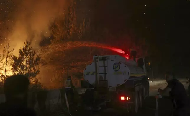 An emergency responder with the Syrian Civil Defense, known as the White Helmets, works to extinguish a wildfire in the town of Rabia, in Latakia province, Syria, Saturday, July 5, 2025. (AP Photo/Ghaith Alsayed)