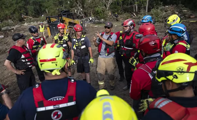A crew of firefighters from Ciudad Acuna, Mexico, gather for a briefing as they aid in search and rescue efforts near the Guadalupe River after a flash flood swept through the area Monday, July 7, 2025, in Ingram, Texas. (AP Photo/Eli Hartman)