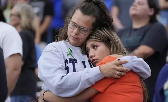 Attendees hug during a vigil for flooding victims at Tivy Antler Stadium on Wednesday, July 9, 2025, in Kerrville, Texas. (AP Photo/Ashley Landis)