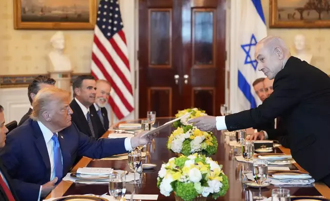 Israel's Prime Minister Benjamin Netanyahu, right, hands President Donald Trump a folder during a meeting in the Blue Room of the White House, Monday, July 7, 2025, in Washington. (AP Photo/Alex Brandon)