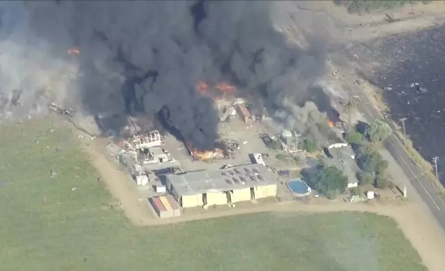 In this aerial image taken from video, smoke and flames rise from a fireworks warehouse explosion, July 1, 2025, Esparto, Calif. (KGO via AP)