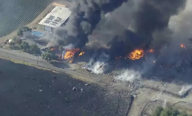 In this aerial image taken from video, smoke and flames rise from a fireworks warehouse explosion, July 1, 2025, Esparto, Calif. (KGO via AP)