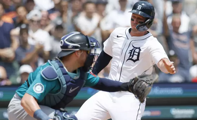 Detroit Tigers' Spencer Torkelson, right, scores past Seattle Mariners catcher Mitch Garver on a double by Dillon Dingler during the first inning of a baseball game Sunday, July 13, 2025, in Detroit. (AP Photo/Duane Burleson)