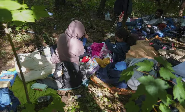 Anouar, from Yemen, holds her daughter Kadi, 4, while her second daughter Jori, 6, center, right, and husband Qassim, from Palestine, right, wait in the forest of Ecault, northern France, Thursday, July 3, 2025. (AP Photo/Nicolas Garriga)
