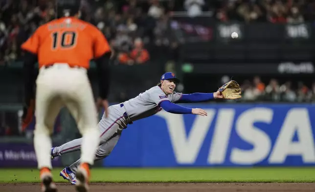 San Francisco Giants' Casey Schmitt, foreground, watches as New York Mets second baseman Brett Baty is unable to catch a single hit by Patrick Bailey during the fifth inning of a baseball game Friday, July 25, 2025, in San Francisco. (AP Photo/Godofredo A. Vásquez)