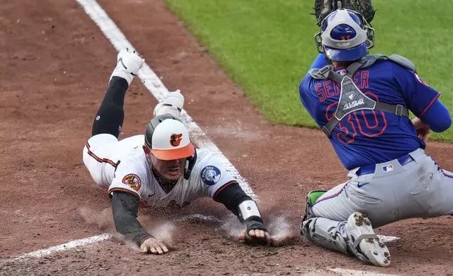 Baltimore Orioles' Alex Jackson, left, slides to score in front of New York Mets catcher Hayden Senger (30) during the seventh inning in the second baseball game of a doubleheader, Thursday, July 10, 2025, in Baltimore. (AP Photo/Stephanie Scarbrough)
