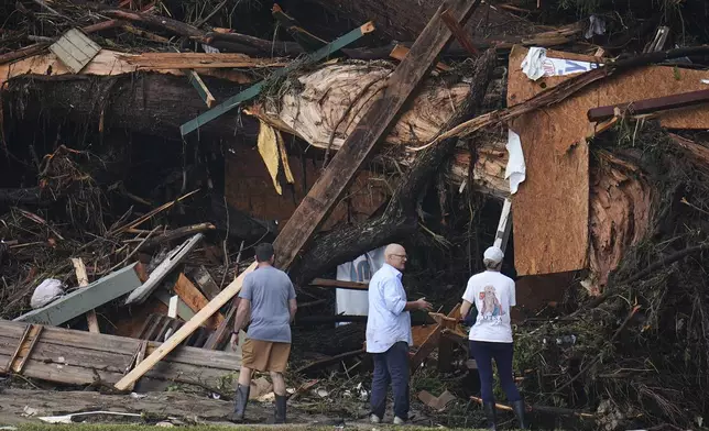 People look at debris on the banks of the Guadalupe River after a flash flood swept through the area Saturday, July 5, 2025, in Hunt, Texas. (AP Photo/Julio Cortez)