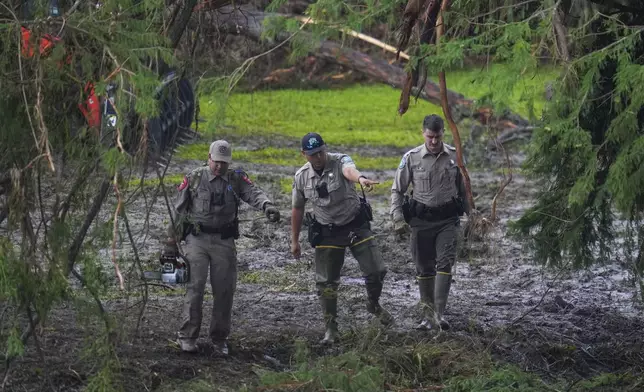 Officials inspect an area at Camp Mystic along the banks of the Guadalupe River after a flash flood swept through the area Sunday, July 6, 2025, in Hunt, Texas. (AP Photo/Julio Cortez)
