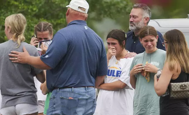 People comfort each other outside the Butt-Holdsworth Memorial Library in Kerville after heavy rainfall caused the Guadalupe River to flood and damage several communities in Central Texas, Saturday, July 5, 2025. (Jason Fochtman/Houston Chronicle via AP)