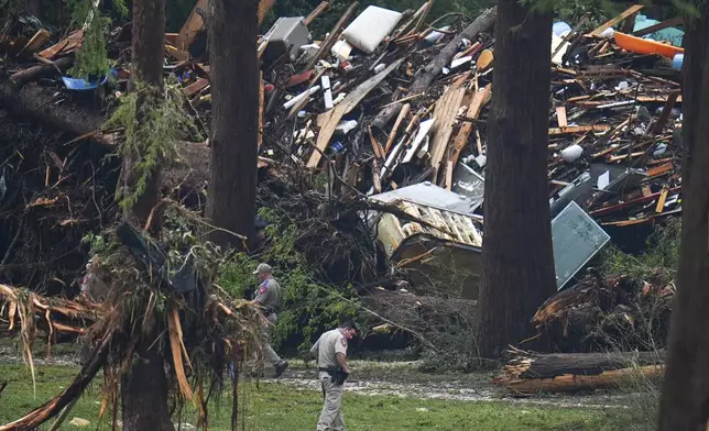 Officials comb through the banks of the Guadalupe River after a flash flood swept through the area Saturday, July 5, 2025, in Hunt, Texas. (AP Photo/Julio Cortez)