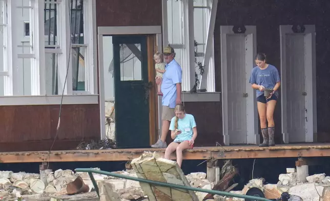 A person salvages a bell from the main building at Camp Mystic along the banks of the Guadalupe River after a flash flood swept through the area Sunday, July 6, 2025, in Hunt, Texas. (AP Photo/Julio Cortez)