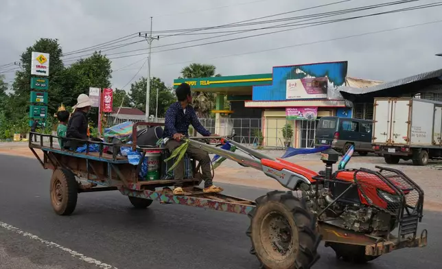A Cambodian family returning home from a temporary shelter drive past a gas station damaged in Phrong village, Oddar Meanchey province, Cambodia, Wednesday, July 30, 2025, after a ceasefire to end deadly border clashes was reached between Thailand and Cambodia. (AP Photo/Heng Sinith)
