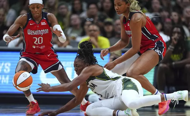 Washington Mystics guard Brittney Sykes (20) reaches for the ball as Seattle Storm forward Nneka Ogwumike, front right, loses possession and Mystics forward Kiki Iriafen looks on during the second half of a WNBA basketball game Sunday, July 13, 2025, in Seattle. (AP Photo/Lindsey Wasson)
