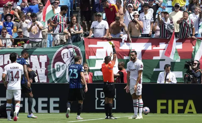 Referee Ivan Arcides Barton Cisneros, of El Salvador, shows the yellow card to Fluminense's Juan Pablo Freytes during the Club World Cup round of 16 soccer match between Inter Milan and Fluminense in Charlotte, N.C., Monday, June 30, 2025. (AP Photo/Chris Carlson)