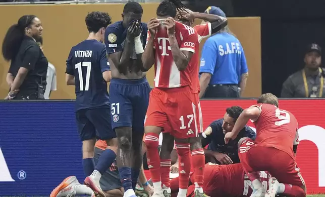 Bayern Munich's Michael Olise, foreground, and Paris Saint-Germain's Willian Pacho cover their faces while Bayern Munich's Jamal Musiala lies on the ground during the Club World Cup quarterfinal soccer match between PSG and Bayern Munich in Atlanta, Saturday, July 5, 2025. (AP Photo/Mike Stewart)